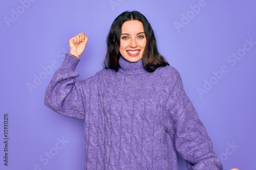 Young beautiful woman wearing casual turtleneck sweater standing over purple background Dancing happy and cheerful, smiling moving casual and confident listening to music © Krakenimages.com