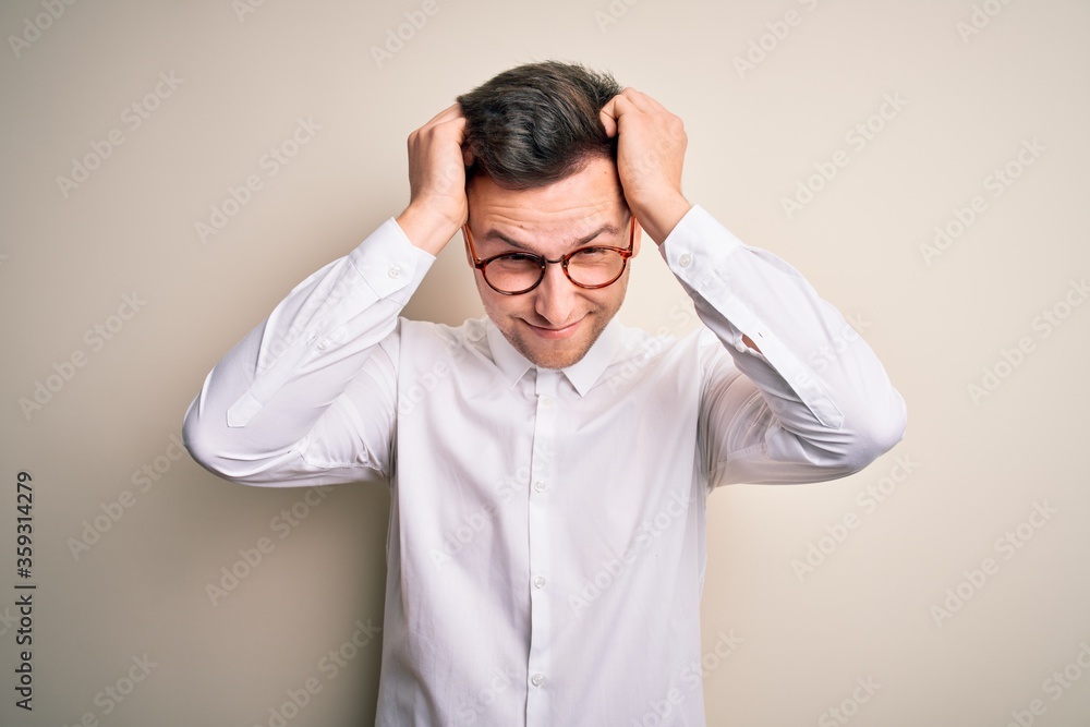 Young handsome business mas wearing glasses and elegant shirt over isolated background suffering from headache desperate and stressed because pain and migraine. Hands on head. Young handsome business mas wearing glasses and elegant shirt over isolated background suffering from headache desperate and stressed because pain and migraine. Hands on head.