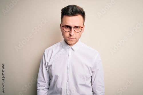 Young handsome business mas wearing glasses and elegant shirt over isolated background skeptic and nervous, frowning upset because of problem. Negative person.