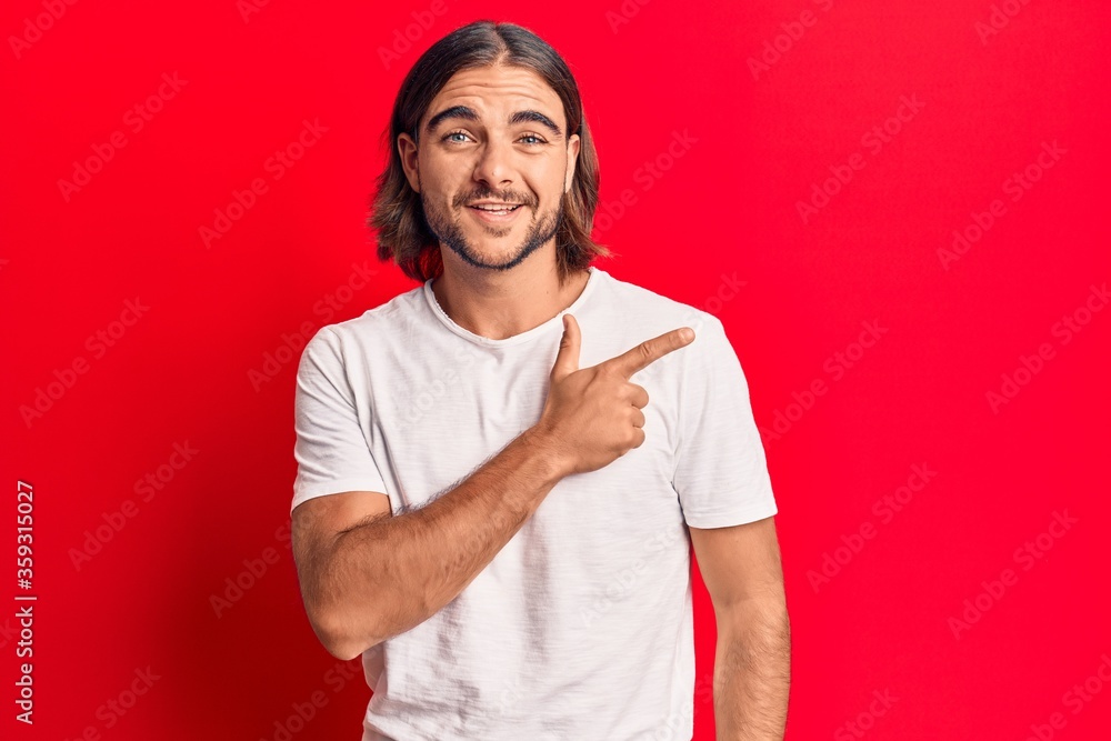 Young handsome man wearing casual clothes cheerful with a smile of face pointing with hand and finger up to the side with happy and natural expression on face Young handsome man wearing casual clothes cheerful with a smile of face pointing with hand and finger up to the side with happy and natural expression on face