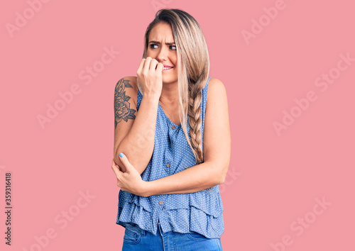Young beautiful blonde woman wearing casual sleeveless t-shirt looking stressed and nervous with hands on mouth biting nails. anxiety problem.