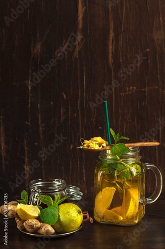 Homemade lemonade for weight loss with ginger and lime in a glass Cup and ingredients on a dark background, low key
