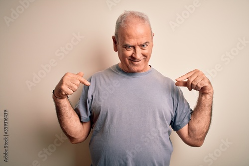 Middle age handsome hoary man wearing t-shirt standing over isolated white background looking confident with smile on face, pointing oneself with fingers proud and happy.