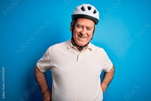 Middle age hoary cyclist man wearing bike security helmet over isolated blue background with a happy and cool smile on face. Lucky person.