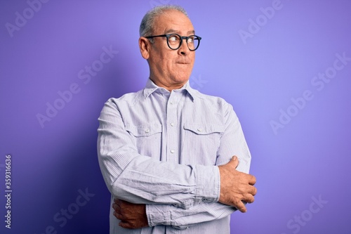 Middle age handsome hoary man wearing striped shirt and glasses over purple background smiling looking to the side and staring away thinking.