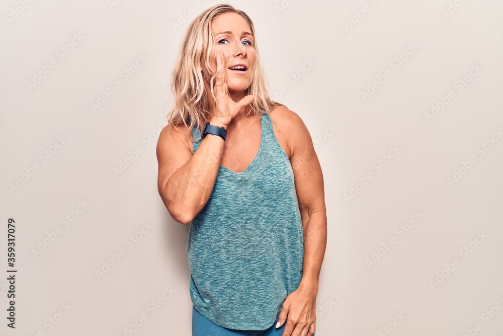 Naklejka premium Middle age caucasian blonde woman wearing sportswear hand on mouth telling secret rumor, whispering malicious talk conversation