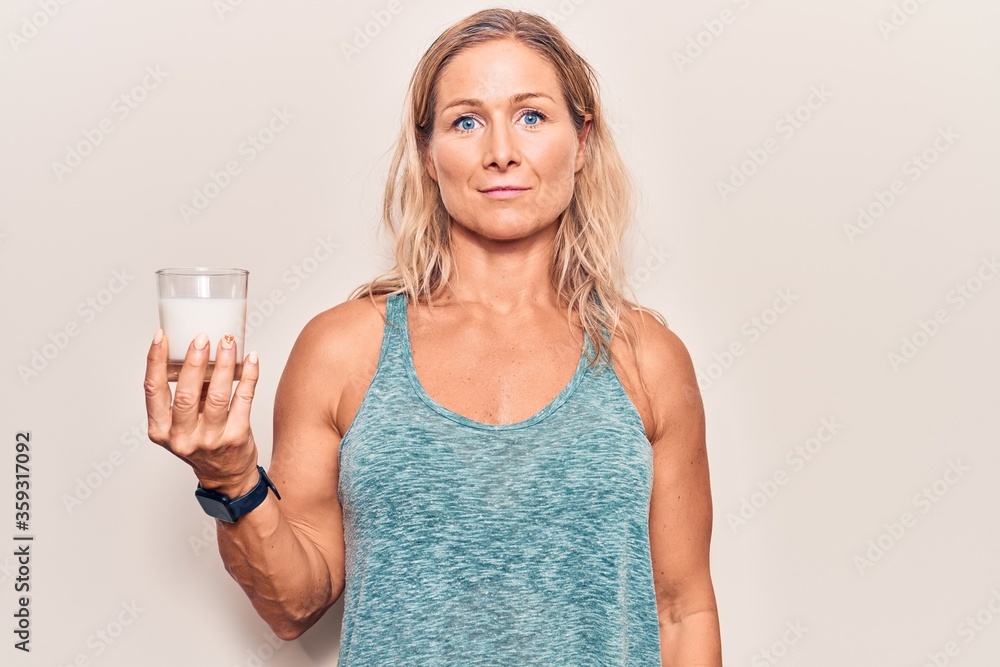 Middle age caucasian blonde woman holding a glass of milk thinking attitude and sober expression looking self confident Middle age caucasian blonde woman holding a glass of milk thinking attitude and sober expression looking self confident