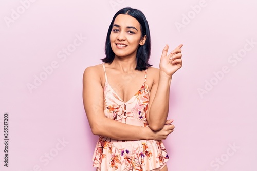 Young beautiful latin woman wearing casual clothes with a big smile on face, pointing with hand and finger to the side looking at the camera. © Krakenimages.com