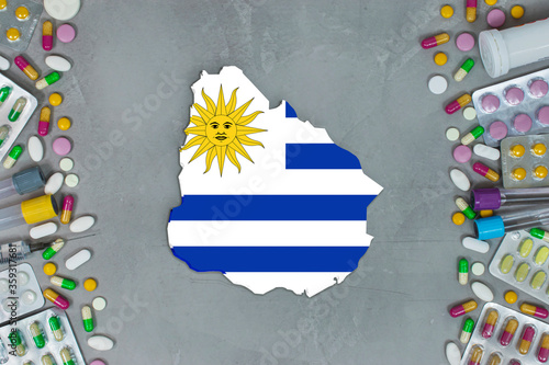 The Uruguay State began research for treatment and medicine to combat the pandemic outbreak disease coronavirus. Medicine, pills, needles, syringes and Uruguay map and flag on gray background.