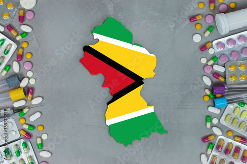 The Guyana State began research for treatment and medicine to combat the pandemic outbreak disease coronavirus. Medicine, pills, needles, syringes and Guyana map and flag on gray background.