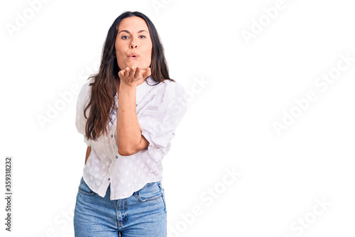 Young beautiful brunette woman wearing casual shirt looking at the camera blowing a kiss with hand on air being lovely and sexy. love expression. © Krakenimages.com