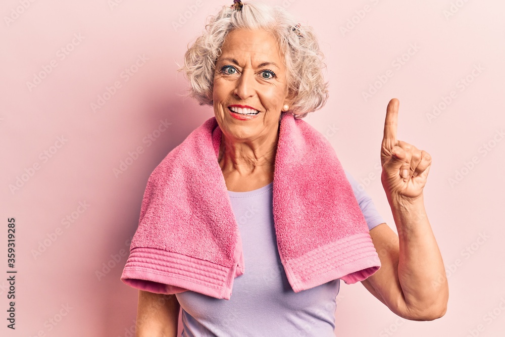 Senior grey-haired woman wearing sportswear and towel smiling with an idea or question pointing finger up with happy face, number one Senior grey-haired woman wearing sportswear and towel smiling with an idea or question pointing finger up with happy face, number one