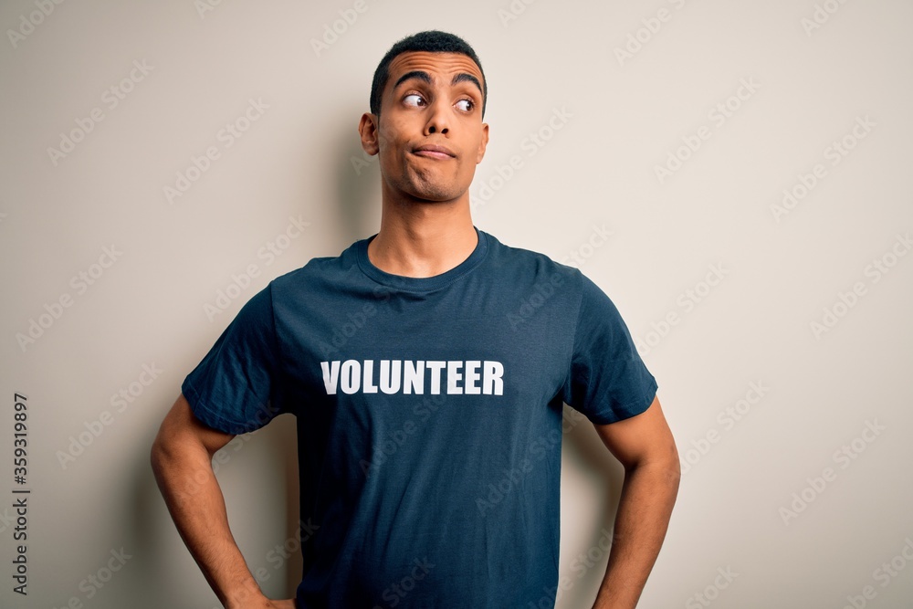 Young handsome african american man volunteering wearing t-shirt with volunteer message smiling looking to the side and staring away thinking. Young handsome african american man volunteering wearing t-shirt with volunteer message smiling looking to the side and staring away thinking.