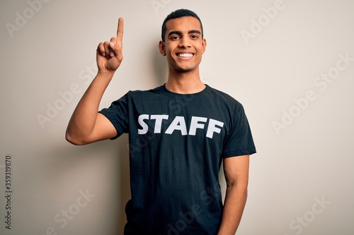 Young handsome african american worker man wearing staff uniform over white background with a big smile on face, pointing with hand finger to the side looking at the camera. © Krakenimages.com