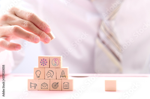 Businessman hand holding wooden cube block with business icons and business idea concept