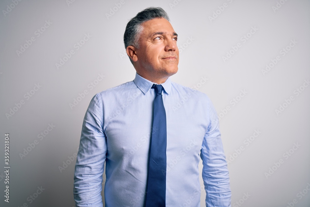 Middle age handsome grey-haired business man wearing elegant shirt and tie looking away to side with smile on face, natural expression. Laughing confident. Middle age handsome grey-haired business man wearing elegant shirt and tie looking away to side with smile on face, natural expression. Laughing confident.