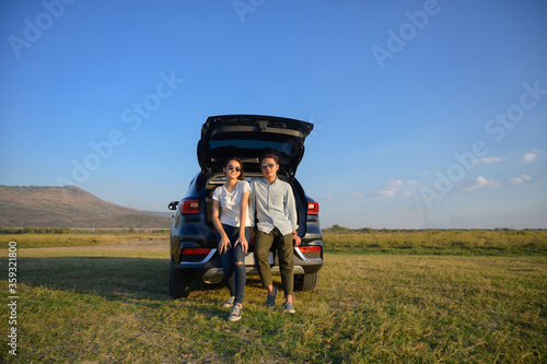 Young couple happy asian out on a road trip. Asian couple Man  and woman sitting on back of car travel to mountain and lake in holiday with car road trip