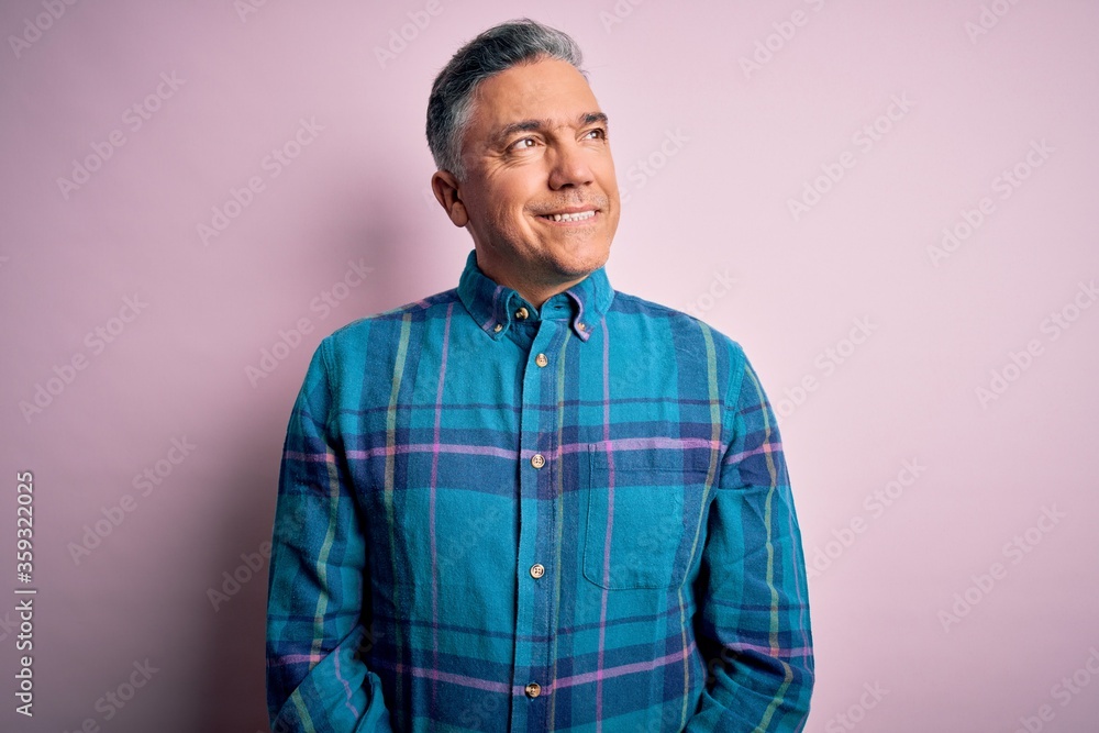 Middle age handsome grey-haired man wearing casual shirt over isolated pink background looking away to side with smile on face, natural expression. Laughing confident. Middle age handsome grey-haired man wearing casual shirt over isolated pink background looking away to side with smile on face, natural expression. Laughing confident.