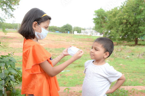 AN INDIAN LITTLE GIRL TEACHES HER YOUNGER BROTHER HOW TO WEAR MASK  FOR PREVENTION FROM  CORONA VIRUS