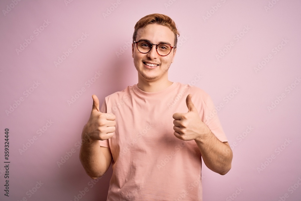 Young handsome redhead man wearing casual t-shirt standing over isolated pink background success sign doing positive gesture with hand, thumbs up smiling and happy. Cheerful expression and winner Young handsome redhead man wearing casual t-shirt standing over isolated pink background success sign doing positive gesture with hand, thumbs up smiling and happy. Cheerful expression and winner