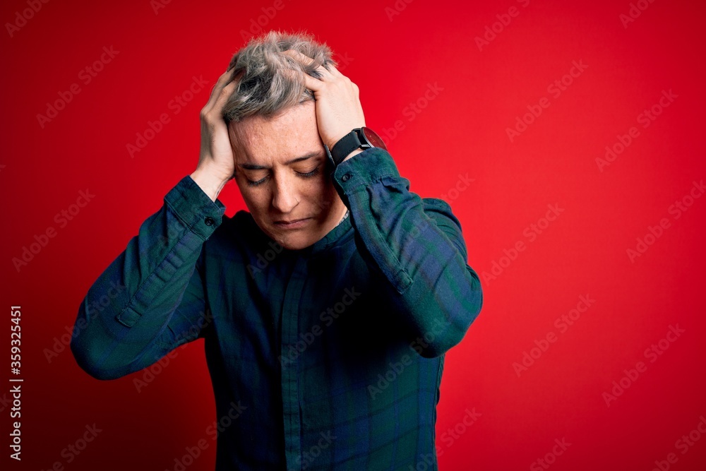 Young handsome modern man wearing elegant green shirt over red isolated background suffering from headache desperate and stressed because pain and migraine. Hands on head. Young handsome modern man wearing elegant green shirt over red isolated background suffering from headache desperate and stressed because pain and migraine. Hands on head.