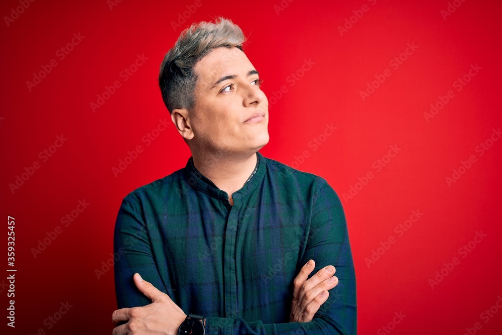 Obraz premium Young handsome modern man wearing elegant green shirt over red isolated background looking to the side with arms crossed convinced and confident
