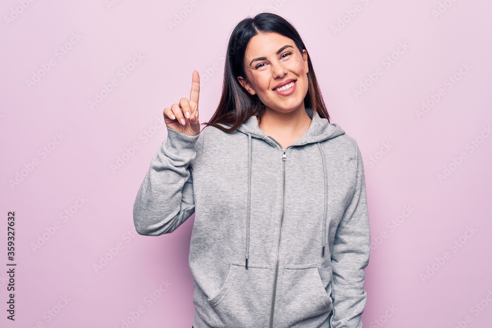 Young beautiful sporty woman wearing sportswear standing over isolated pink background smiling with an idea or question pointing finger up with happy face, number one Young beautiful sporty woman wearing sportswear standing over isolated pink background smiling with an idea or question pointing finger up with happy face, number one
