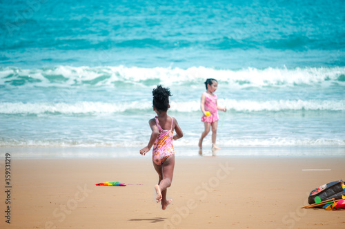 Little cute kid girl  having fun on sandy summer with blue sea, happy childhood friend running and  playing on tropical beach