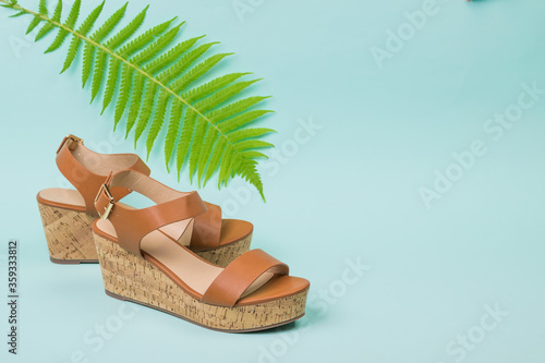 Women's high-soled sandals with a fern leaf on a blue background. photo