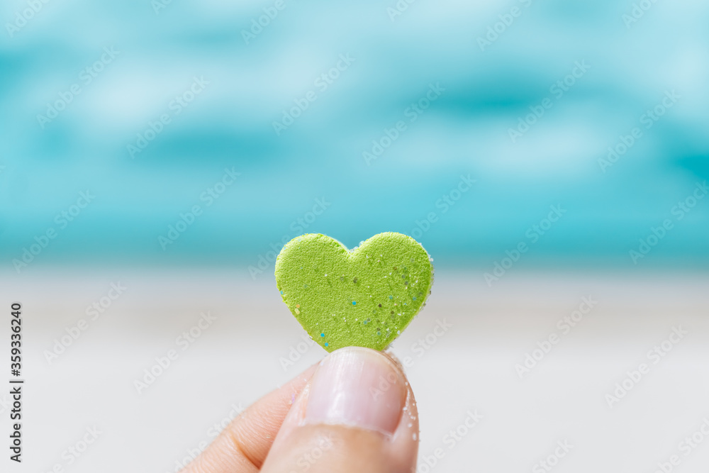 Fototapeta premium Hand hold little heart meaning feel love with summer beach with blue sky.