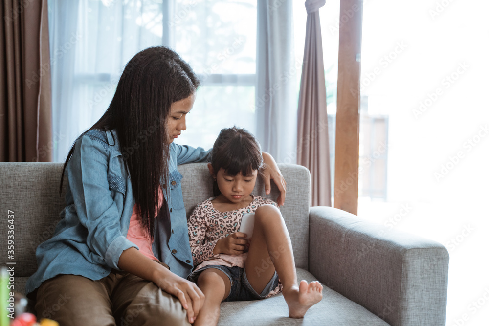 Obraz premium sibling different age using mobile phone together while stay home