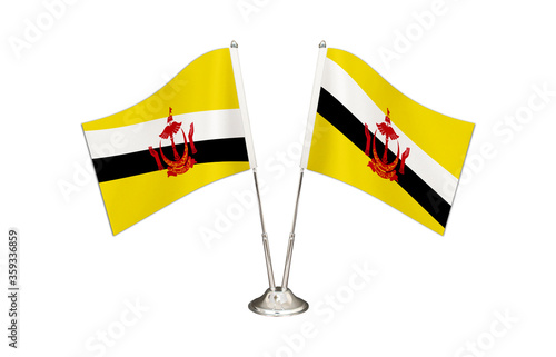 Brunei table flag isolated on white ground. Two flag poles with flags and Brunei flag on the table. photo