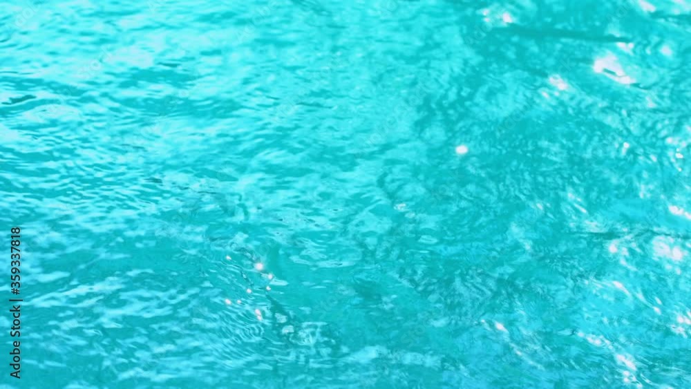 Beautiful sparkling shiny texture of blurry blue water with sun reflected on surface of water Beautiful sparkling shiny texture of blurry blue water with sun reflected on surface of water