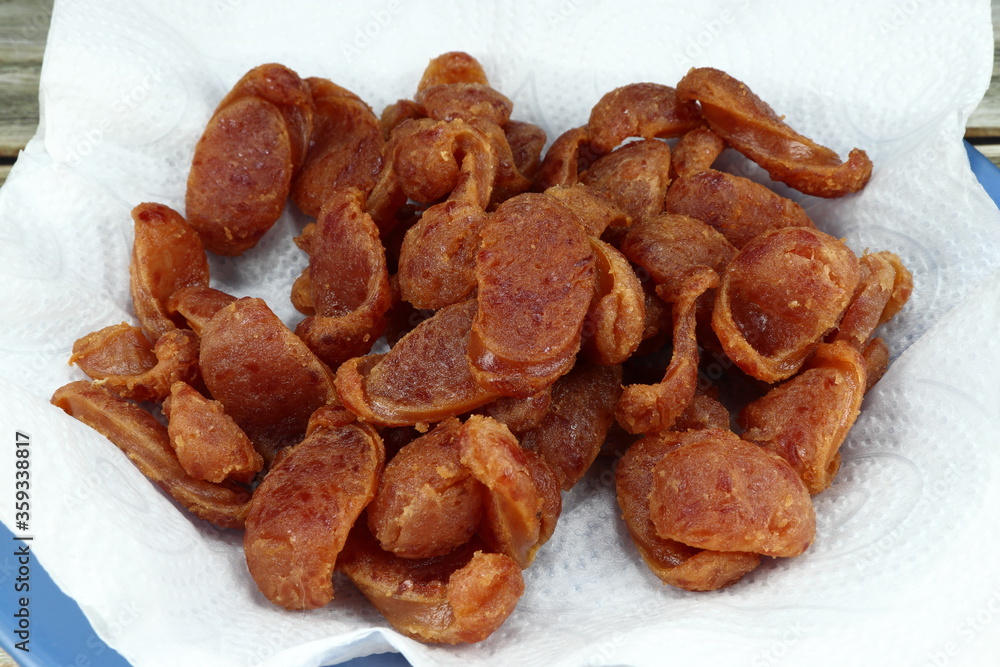Obraz premium Pile of deep fried cutting Chinese pork sausage on the food oil absorption paper (Oil blotting paper). Famous local crispy pork sausage in Asia street food. 