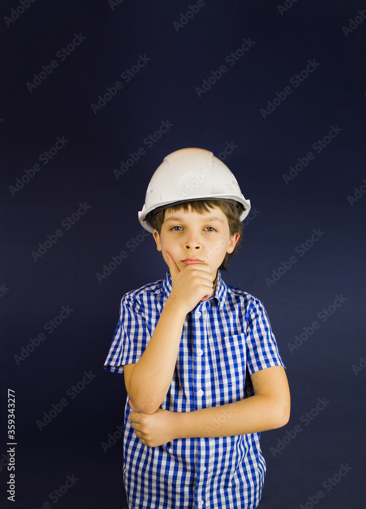 A young guy in a white construction helmet or protective helmet to think or reflect.