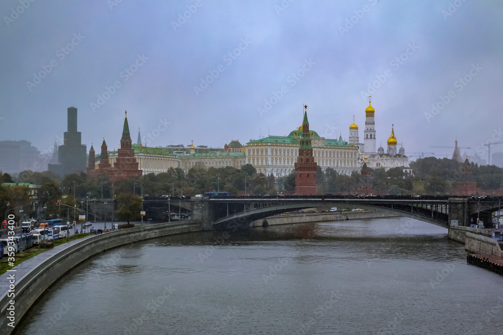 Red Kremlin wall and tower, traffic on Kremlevskaya Embankment by the Moskva River in a snow storm in Moscow, Russia