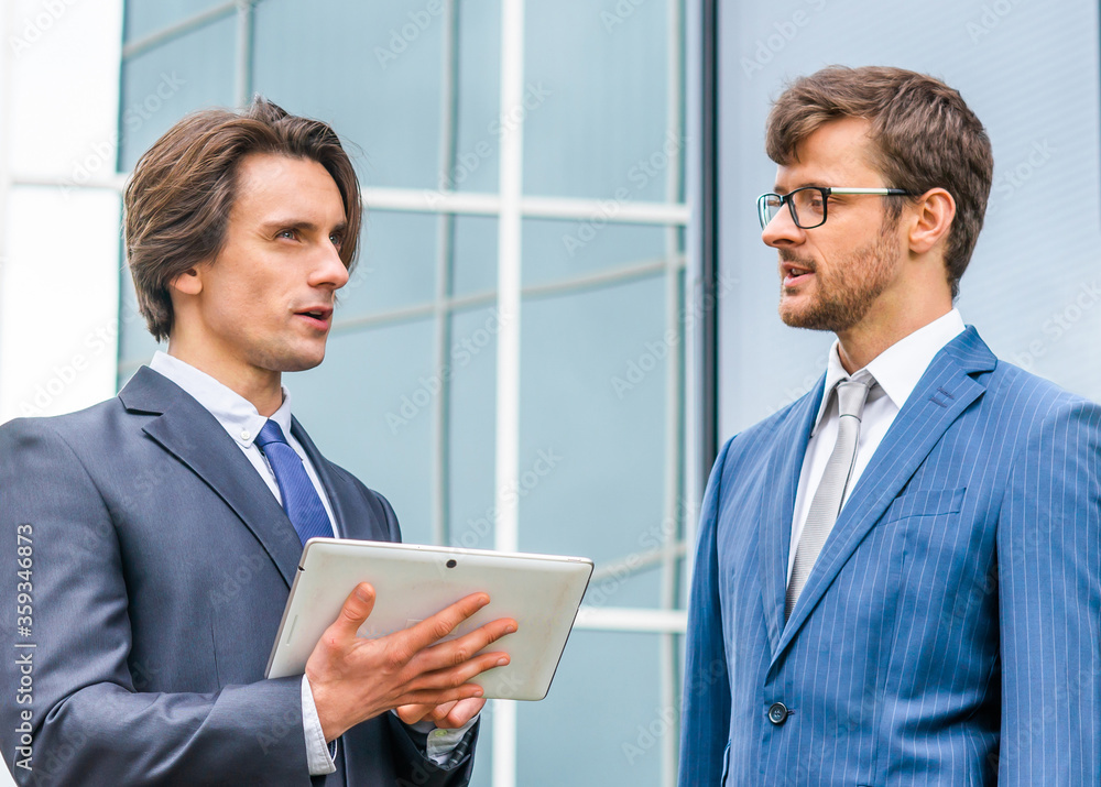 Confident businesspersons in formal wear having conversation about banking and financial markets in front of office building. Confident businesspersons in formal wear having conversation about banking and financial markets in front of office building.