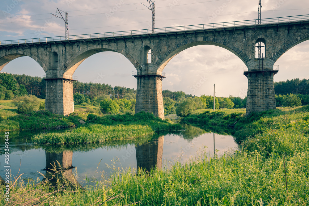 Fototapeta premium Old Arched Stone Railroad Viaduct Bridge over the river. Novohrad-Volynskyi city, Ukraine, Europe