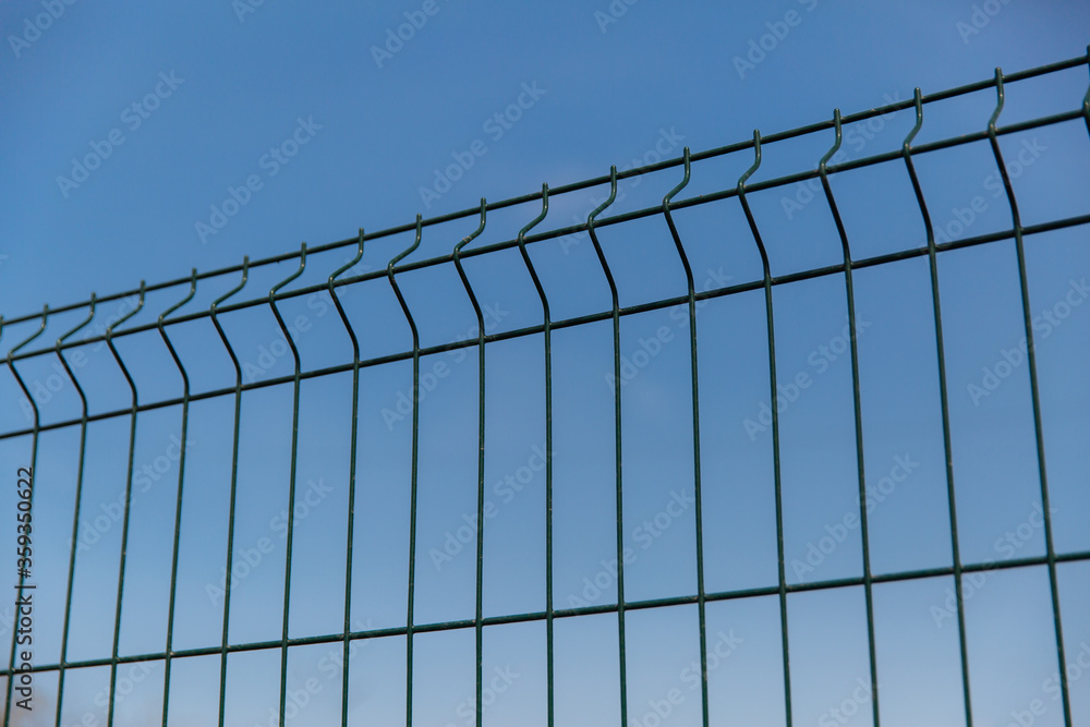 Steel grill fence with wire against the blue sky Steel grill fence with wire against the blue sky