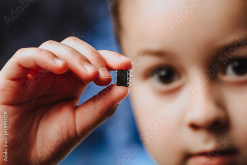 A girl holds in her hand and examines a small black chip. Chipization of people after an epidemic coronavirus.