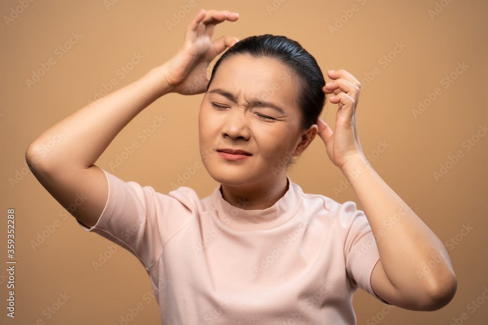 Fototapeta premium Asian woman scratching her head standing isolated on beige background.