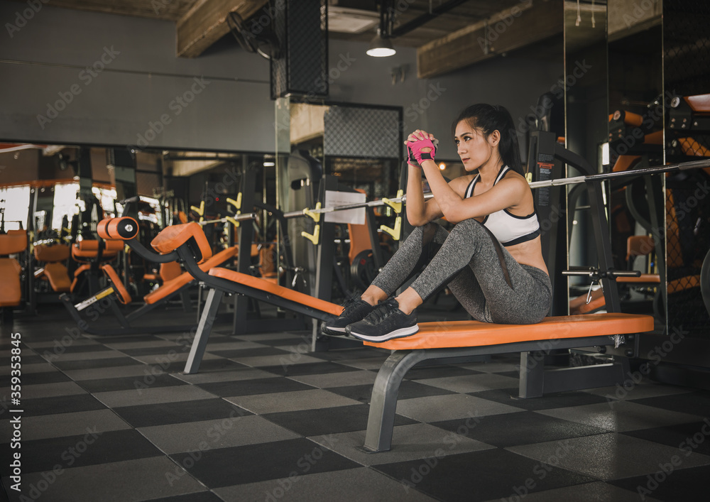 Young Woman Exercising in Gym with Dumbbells, Sitting on Bench and Focusing on Fitness and Strength Training in a Modern Workout Facility Young Woman Exercising in Gym with Dumbbells, Sitting on Bench and Focusing on Fitness and Strength Training in a Modern Workout Facility