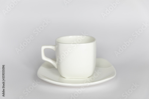 Empty white cup on saucer on white background