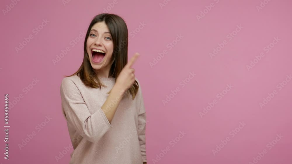 Surprised brunette woman pointing empty place and showing thumbs up, looking with open mouth, amazed expression, showing advertising area for commercial text, copy space. indoor studio shot isolated Surprised brunette woman pointing empty place and showing thumbs up, looking with open mouth, amazed expression, showing advertising area for commercial text, copy space. indoor studio shot isolated