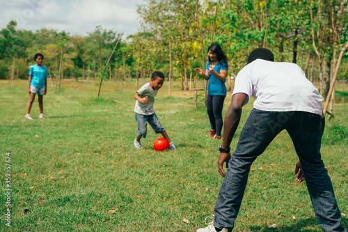 African American family with son and daughter plays a soccer together on the green field for relaxation - Family Bonding Recreation Sports Football Concept