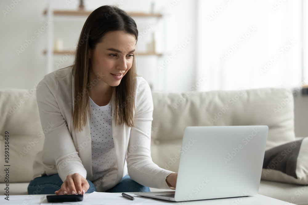 Millennial woman using computer e-bank application calculates incomes feels satisfied. Housewife manage family budget pay domestic utility bills, bookkeeper do work remote job make financial analysis Millennial woman using computer e-bank application calculates incomes feels satisfied. Housewife manage family budget pay domestic utility bills, bookkeeper do work remote job make financial analysis