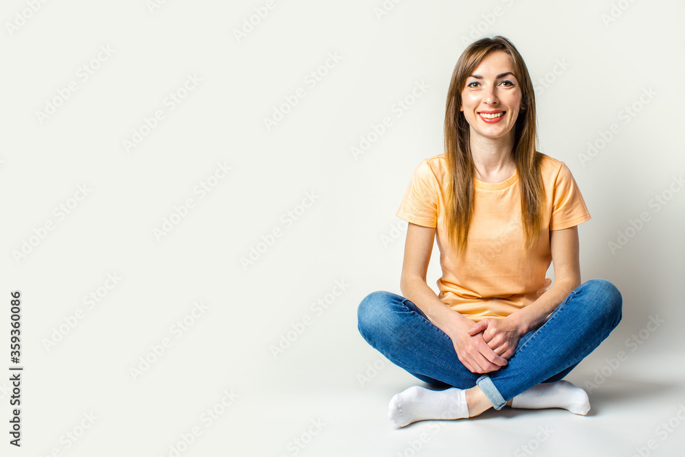 Young woman with a smile sits on the floor on a light background. Banner Young woman with a smile sits on the floor on a light background. Banner