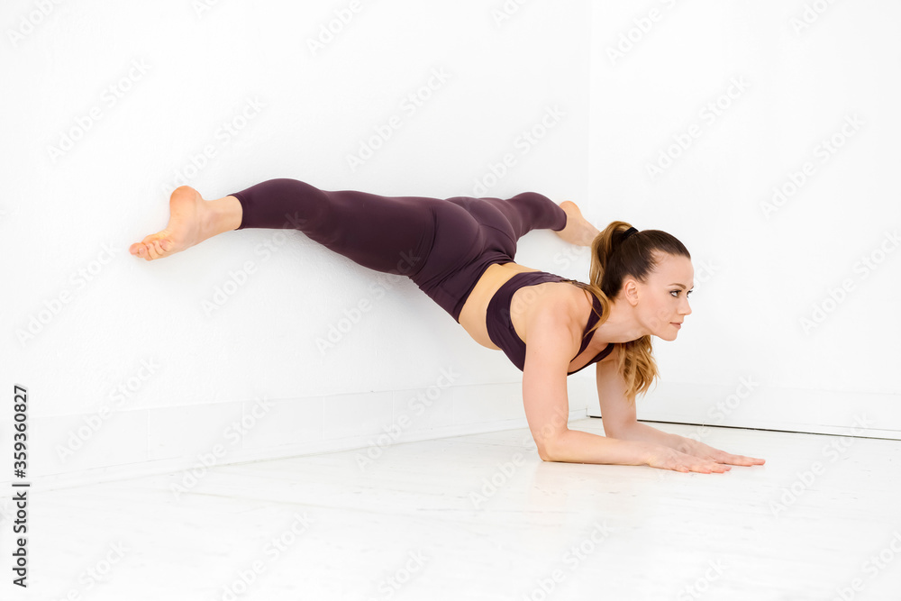 Woman athlete doing an elbow wall split yoga pose Woman athlete doing an elbow wall split yoga pose
