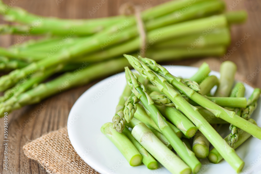 Asparagus on white plate and wooden background - Fresh green asparagus sliced for cooking food