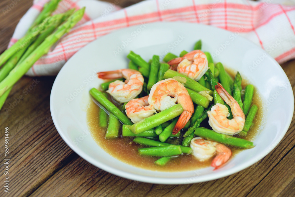 Asparagus Shrimp Seafood Cooked Health Food - Stir fried shrimps with asparagus green on white plate and wooden table background Asparagus Shrimp Seafood Cooked Health Food - Stir fried shrimps with asparagus green on white plate and wooden table background